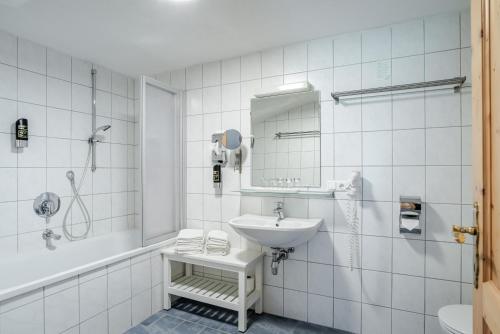 een witte badkamer met een wastafel en een spiegel bij Hotel Kirchdach in Gschnitz