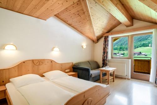een slaapkamer met een bed, een stoel en een raam bij Hotel Kirchdach in Gschnitz