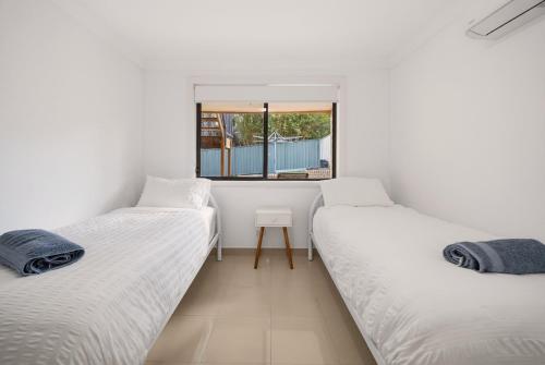 two twin beds in a room with a window at Sapphire By The Sea in Diamond Beach