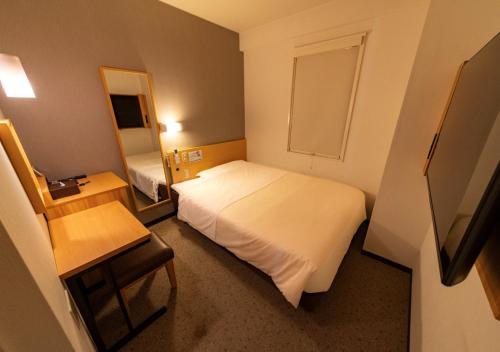 a small bedroom with a white bed and a mirror at Super Hotel Yokkaichi Route 1 in Yokkaichi