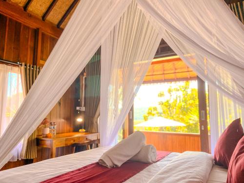 ein Schlafzimmer mit Himmelbett und Fenster in der Unterkunft Desa Hostel in Munduk