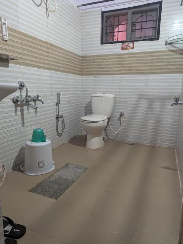 a bathroom with a toilet and a window at Coorg homes in Madikeri