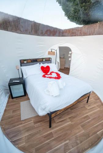 a bed in a tent with a red heart on it at Burbuja El Sueño del Duque in Villanueva de Tapia