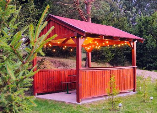 a red gazebo with lights and a bench at Biały Domek Nielbark - Agroturystyka in Nielbark