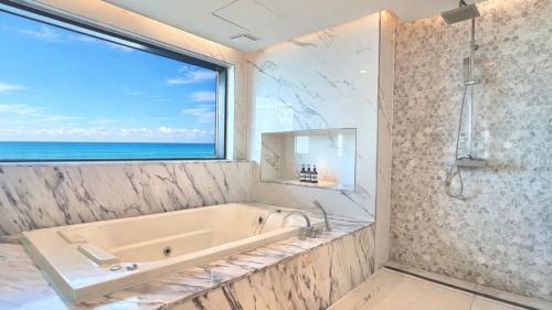 a bathroom with a tub and a window and the ocean at Incheon Grace Hotel in Incheon