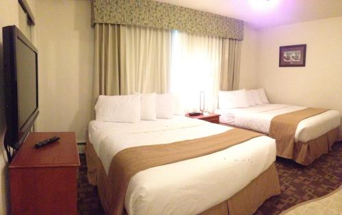 a hotel room with two beds and a television at Alaska's Select Inn Wasilla in Wasilla