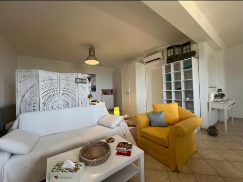 a living room with a bed and a yellow chair at Myrto Signature Suite - Aegina in Aegenitissa