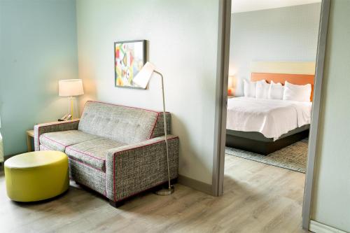 a bedroom with a bed and a chair and a mirror at Home2 Suites By Hilton Jacksonville South St Johns Town Ctr in Jacksonville