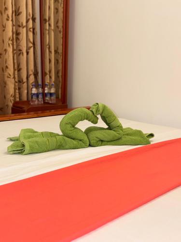 a green stuffed animal laying on a bed at Hotel Camorich in Tissamaharama