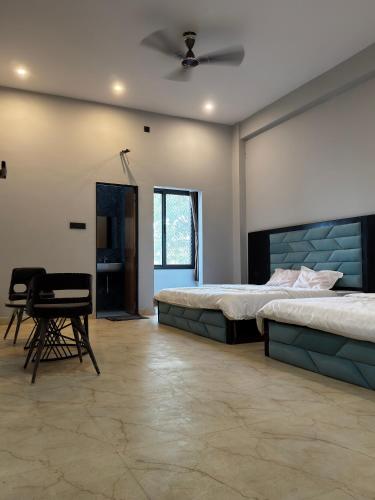 a bedroom with two beds and a table and chairs at Bhagwati Hotel And Rooms in Udaipur