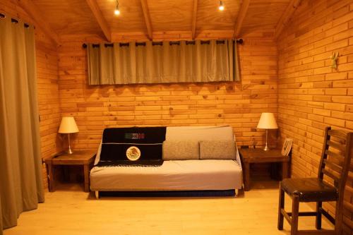 a bedroom with a bed and two tables and a chair at Pinitos Old Ranch & Cabañas in El Cristal