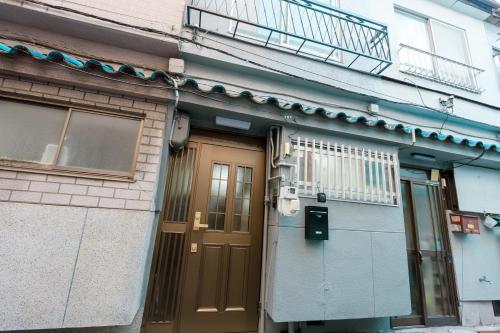a building with a brown door and a balcony at Imafuku Happiness Villa in Osaka