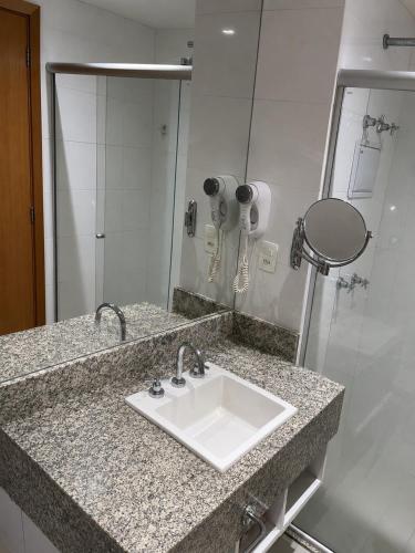 a bathroom counter with a sink and a mirror at Comfortable Serviced Apartment by the Lake in Brasília