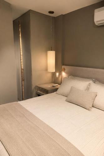 a bedroom with a large white bed with a lamp at Comfortable Serviced Apartment by the Lake in Brasília