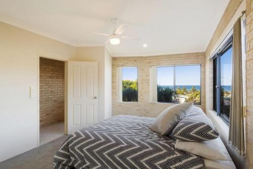 a bedroom with a bed with pillows and windows at Kyeema in Tathra