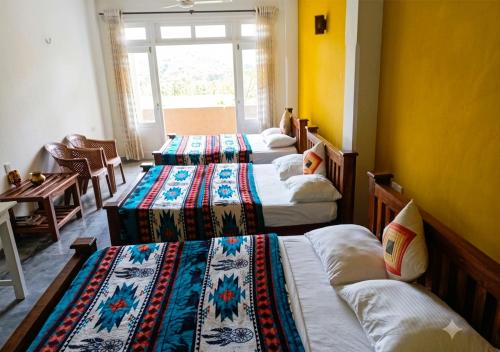 a room with four beds with colorful sheets and a table at Queens Ark in Nallathanniya