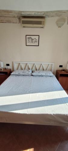 a bedroom with a bed with a blue and white comforter at Dimora Fenni - Appartamento elegante nel cuore di Monte Isola con Wi-Fi e aria condizionata in Monte Isola