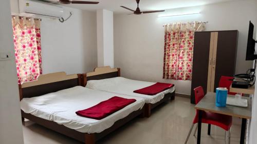 a bedroom with two beds and a desk and a table with a table at Sri Annapurna Residency in Drākshārāma
