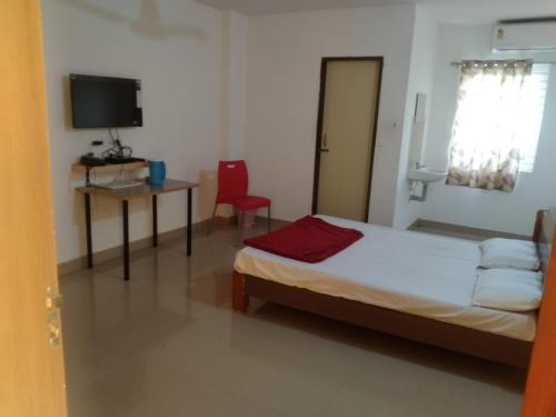 a bedroom with a bed and a desk and a television at Sri Annapurna Residency in Drākshārāma
