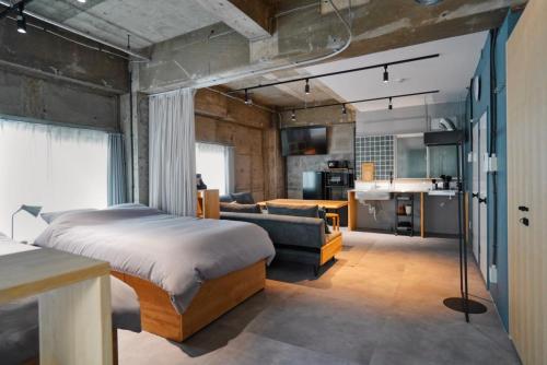 a bedroom with a bed and a couch and a kitchen at Liminal in Atami