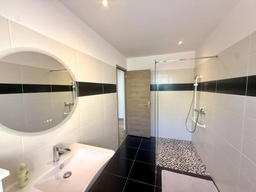 a white bathroom with a sink and a shower at Les Ecrins in Vigneulles-lès-Hattonchâtel