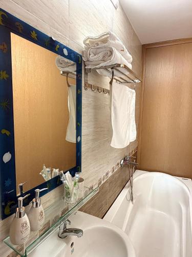 a bathroom with a sink and a mirror and a tub at Khách sạn Lumea in Cam Ranh