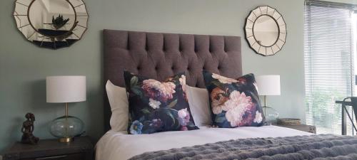 a bedroom with a large bed with pillows and mirrors at Fevertree cottage in Bloemfontein
