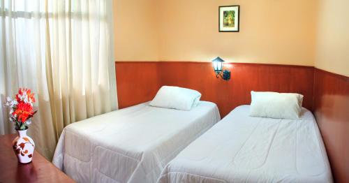 two beds in a room with white sheets at Hotel Princess in Ica
