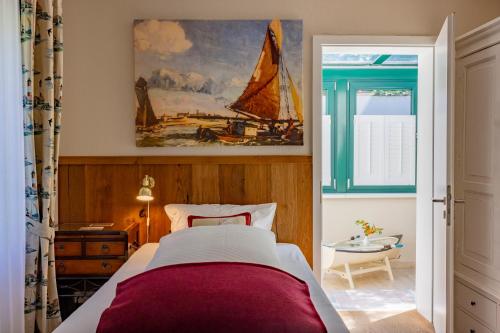 a bedroom with a bed and a painting of a sailboat at Hotel Friese in Norderney