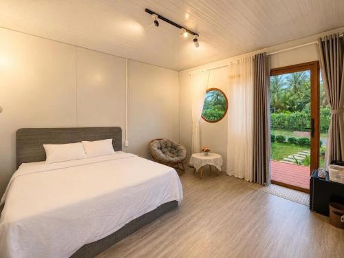 a bedroom with a bed and a window and a chair at Bụi Tre Homestay in Ben Tre