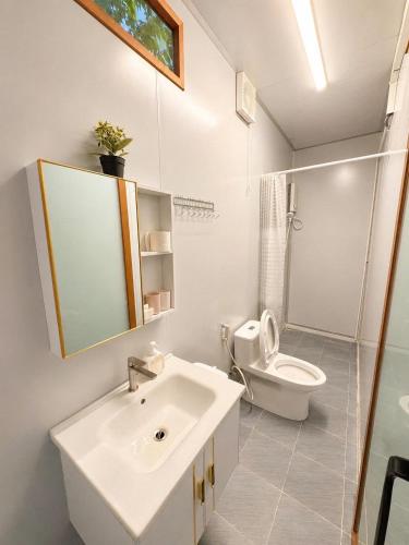 a white bathroom with a sink and a toilet at Bụi Tre Homestay in Ben Tre