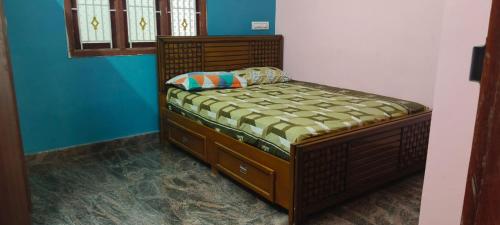 a small bed in a room with blue walls at Thendral Falls View Homestay in Kuttālam