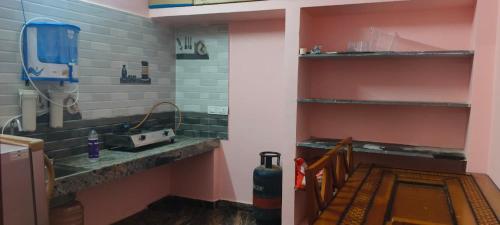a kitchen with a sink and a counter with shelves at Thendral Falls View Homestay in Kuttālam