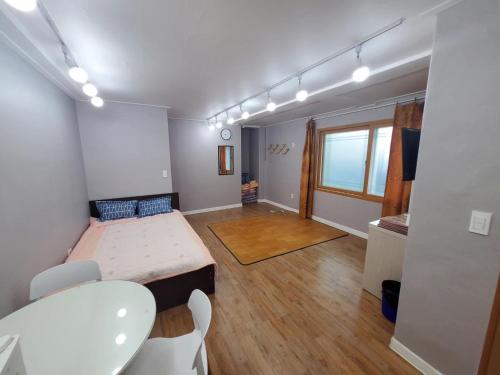 a room with a bed and a table and chairs at 속초푸른바다펜션 in Puwŏl-li
