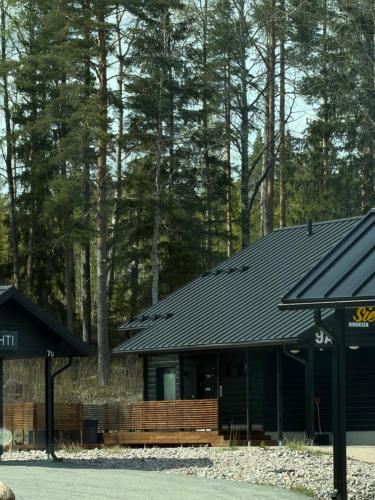 a house with a black roof in the woods at Himos Siesta Porealtaalla ja loppusiivouksella in Jämsä