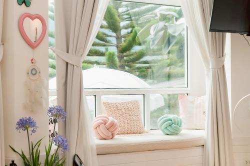 a window seat with pillows in front of a window at Prim's Cottage Khaokho พริม คอทเทจ เขาค้อ วัดผาซ่อนแก้ว in Khao Kho