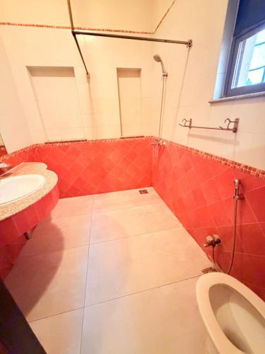 a red bathroom with a toilet and a sink at Comfort Lodge Executive in Islamabad