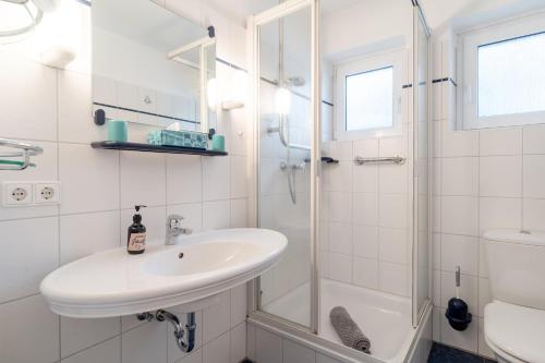 a white bathroom with a sink and a shower at Romantica EG in Sankt Peter-Ording
