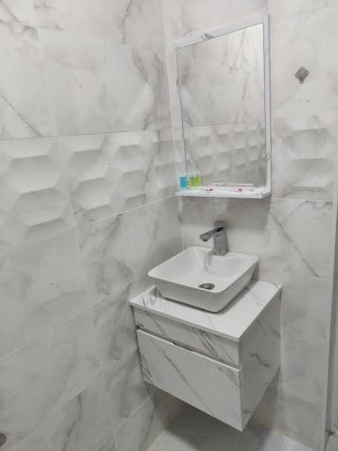 a white bathroom with a sink and a mirror at Hotel RELAX TIME in Lanch'khut'i