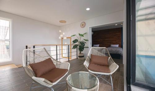 a living room with two chairs and a bed at 판포홈치풀빌라 in Wŏllyŏng