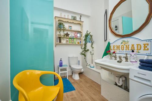 a bathroom with a sink and a mirror and a yellow chair at Enjoy Sandown 1 in Sandown