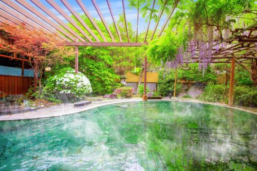 a swimming pool in a garden with a pergola at Ooedo Onsen Monogatari Shinshu Kakeyu in Ueda