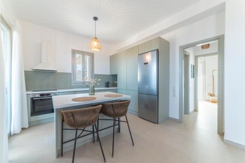 a kitchen with a island with two chairs and a refrigerator at Ayelma - Kythnos Villa in Kithnos
