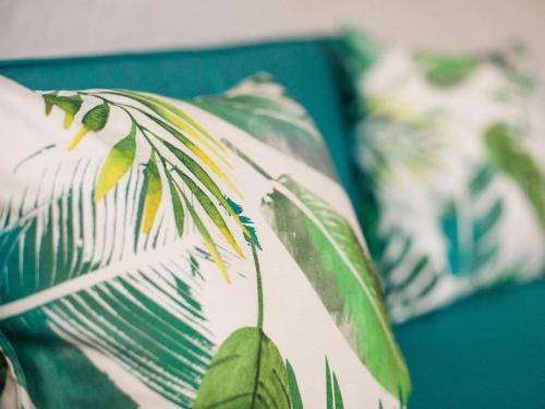 a green and white pillow with leaves on a bed at Boschhuis Apartments - Stellenbosch in Stellenbosch