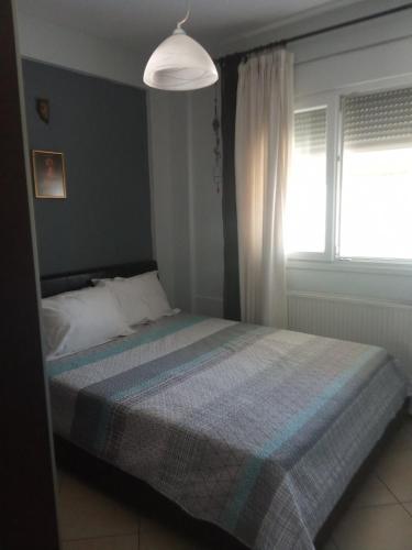 a bedroom with a bed with a blue blanket and a window at SOFI APARTMENT in Ofrínion