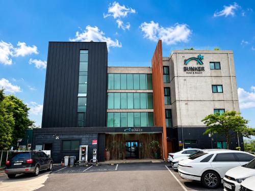 a building with cars parked in a parking lot at Jeju BunkerHotel&Resort in Seogwipo