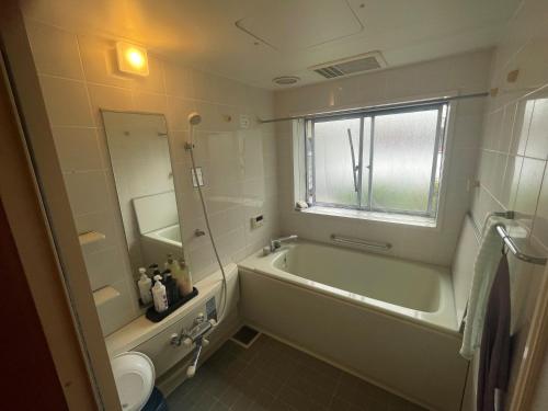a bathroom with a tub and a toilet and a sink at まちやど　Motomachi in Daigo