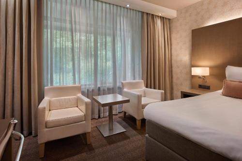 a hotel room with a bed and chairs and a window at Van der Valk Hotel de Bilt-Utrecht in De Bilt