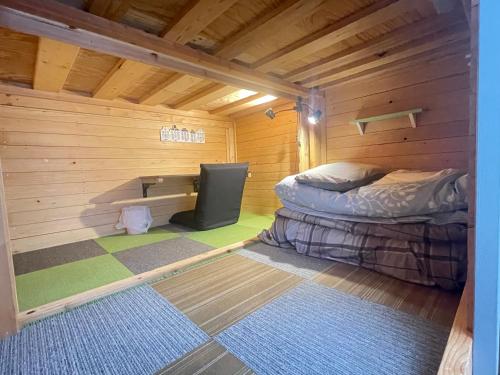 a small room with a bed in a wooden cabin at まちやど　Motomachi in Daigo