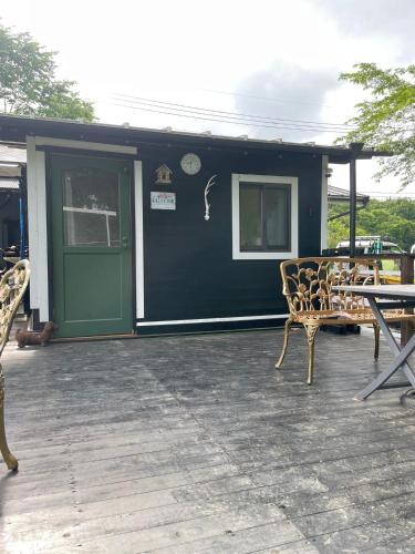 a house with a green door and chairs on a patio at Foresta Karuizawa 7 Glamping & camping for 8 people in Naganohara